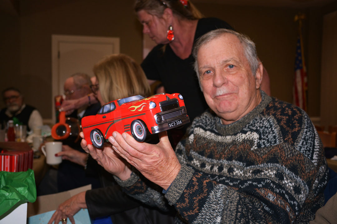 Mark McMillan was surprised to see that his Christmas gift was a car container full of cookies at Post 110's 2023 Christmas Party.  (Photography by Bert Wendell, Jr.)