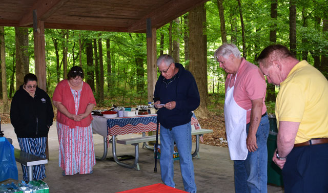 Post Chaplain David Smith (center) offers a prayer prior  to food being served.  In the photo (left to right) are Cyndi Fisher, Tonya Jones, Smith, Ron Basso and Joe Mahacek. (Photography courtesy of Bert Wendell, Jr.)
